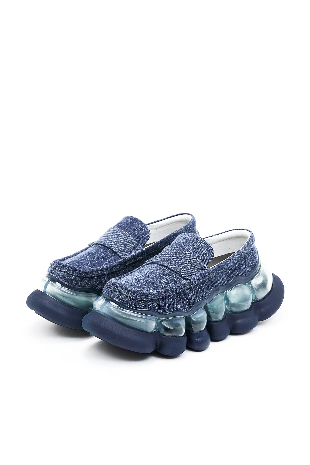 Blue denim penny loafers featuring a sculptural oversized sole with translucent bubble-like side pods and a chunky navy platform, blending classic style with futuristic design.