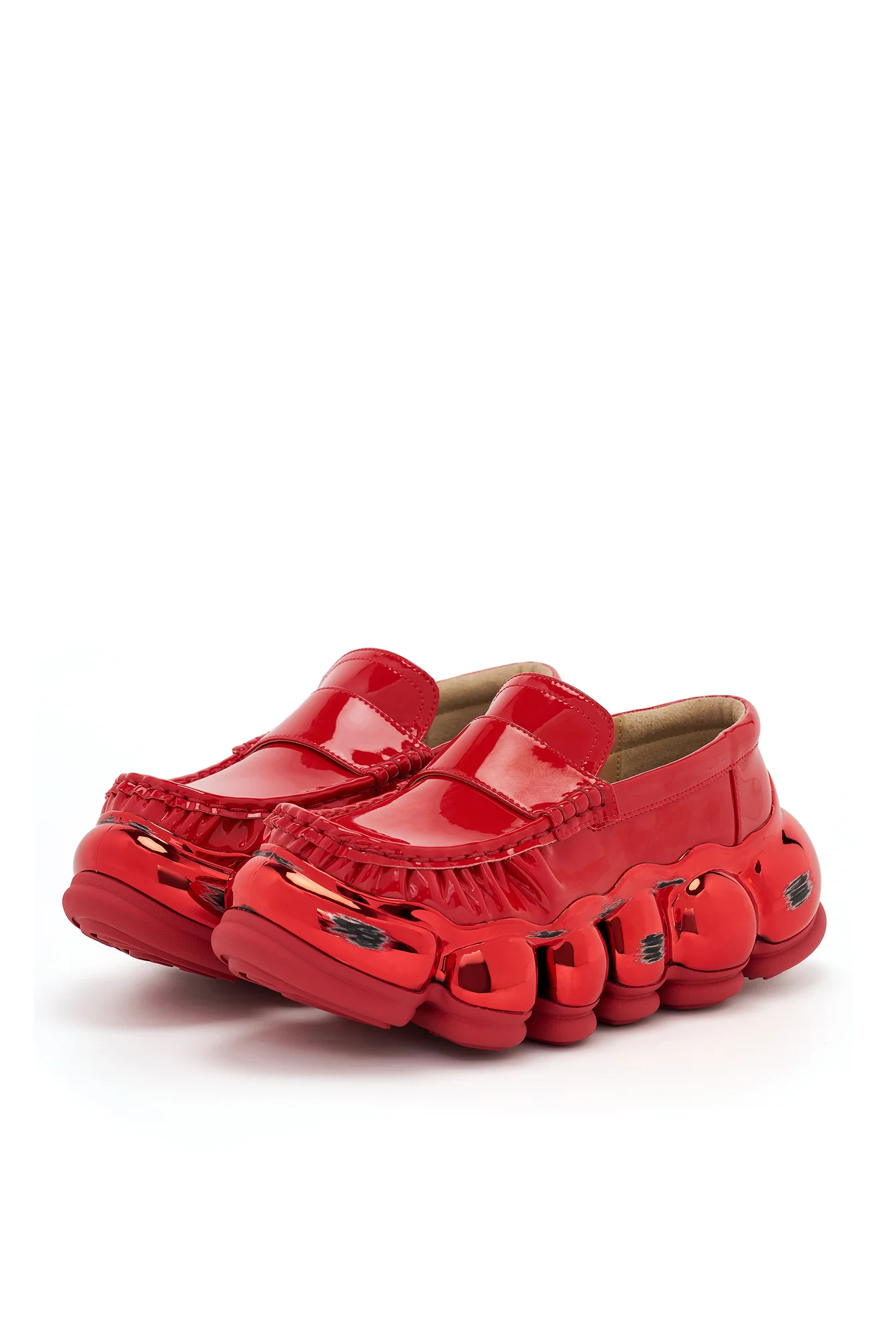 Glossy red penny loafers featuring a sculptural oversized sole with rounded pod-like details, mirror-finish accents, and a bold futuristic silhouette.