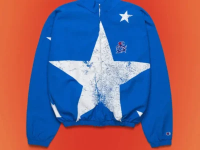 Front view of a royal blue zip-up track jacket with oversized distressed white star artwork, embroidered chest logo, stand collar, elastic cuffs, and Champion branding on the sleeve
