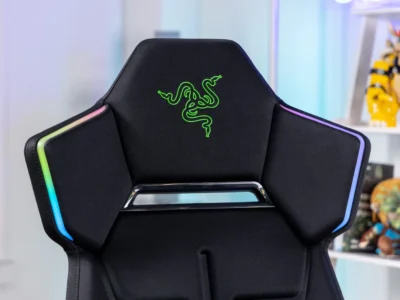 Close up view of Razer gaming chair highlighting the embroidered green Razer logo and RGB Chroma lighting along the shoulder panel