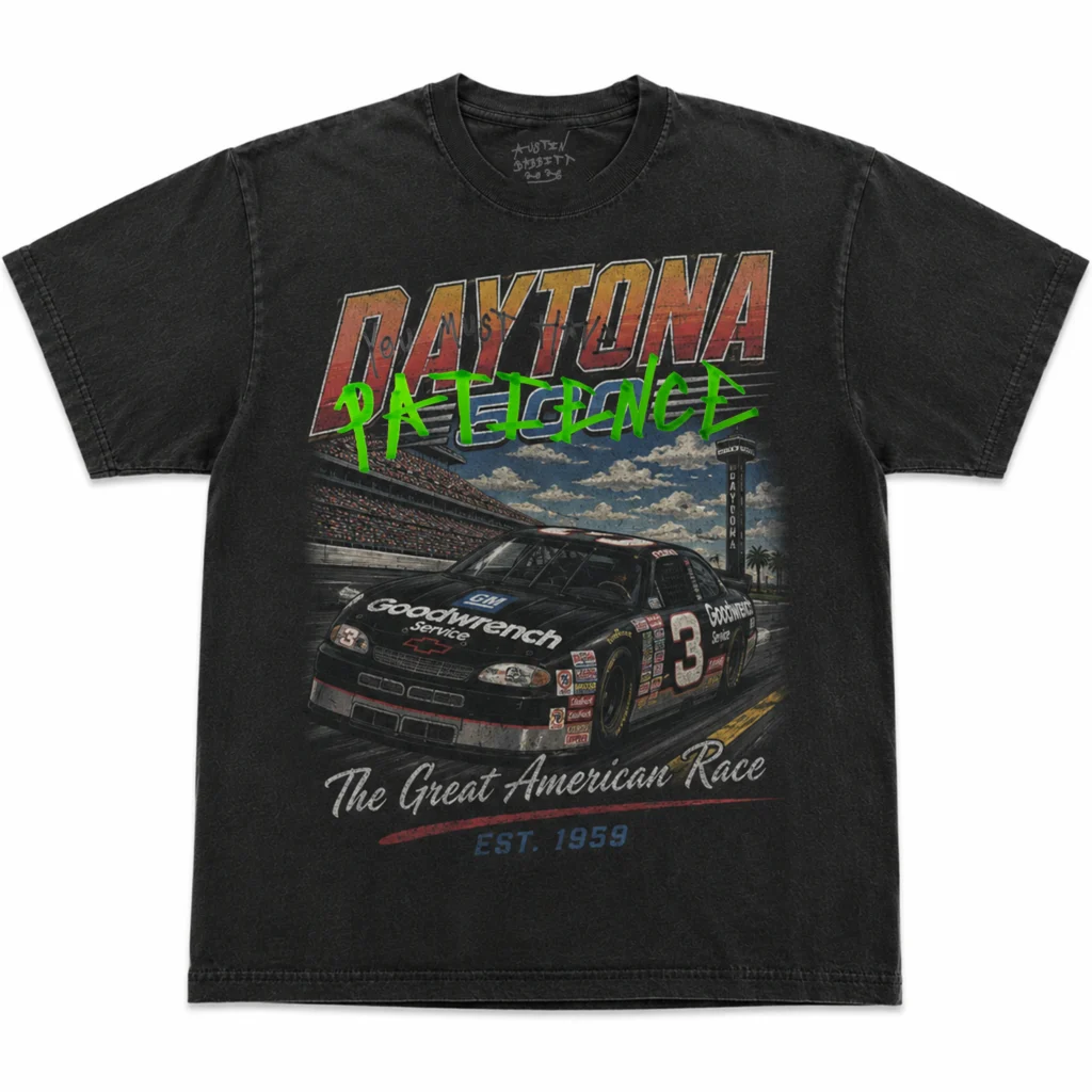 Washed black Tee showcasing a vintage Daytona race car graphic with bold retro lettering, overlaid by a handwritten "You Must Have PATIENCE" design in black and neon green