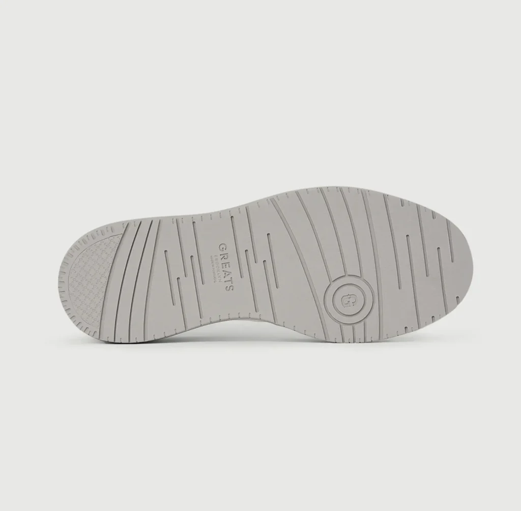 Bottom view of the gray rubber outsole featuring molded traction grooves, embossed branding, and circular pivot detail