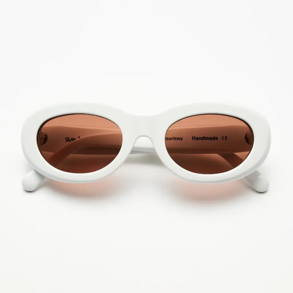 White oval Sun Buddies Courtney sunglasses with soft pink lenses shown from the front