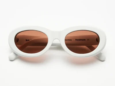 White oval Sun Buddies Courtney sunglasses with soft pink lenses shown from the front
