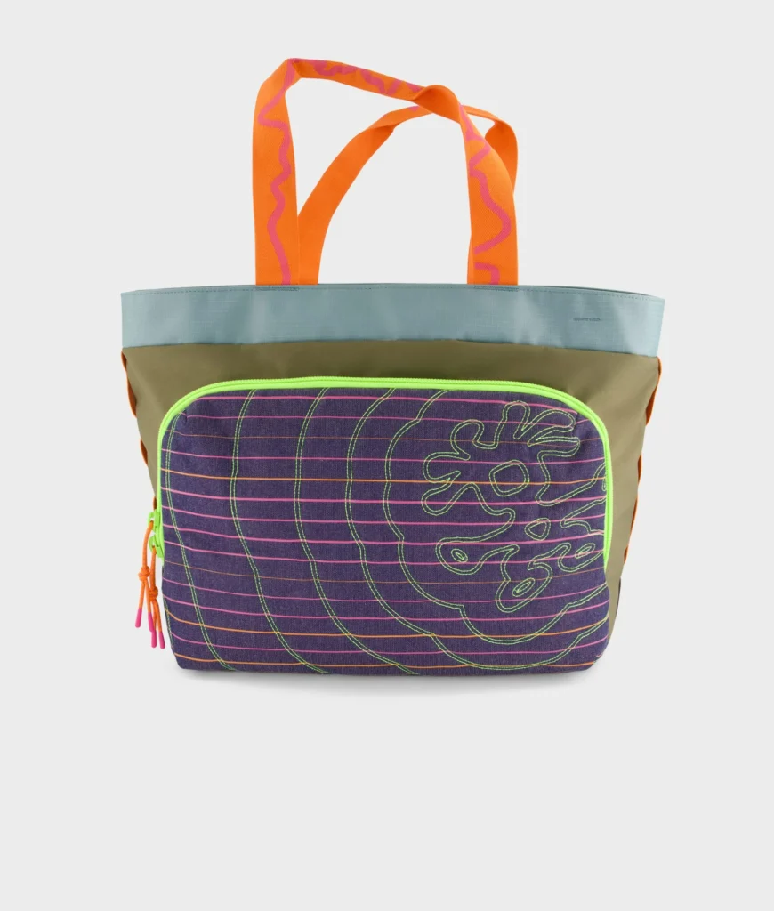 Large Crumpler tote bag featuring olive, teal, purple, and orange color blocking with a neon green front zip pocket, displayed against a clean white background