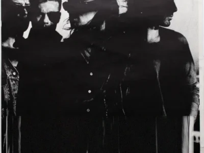 Black-and-white portrait of the four members of U2 standing in shadow against a light background, presented as a minimalist, high-contrast promotional image with the original title text removed, leaving a clean composition focused entirely on the band