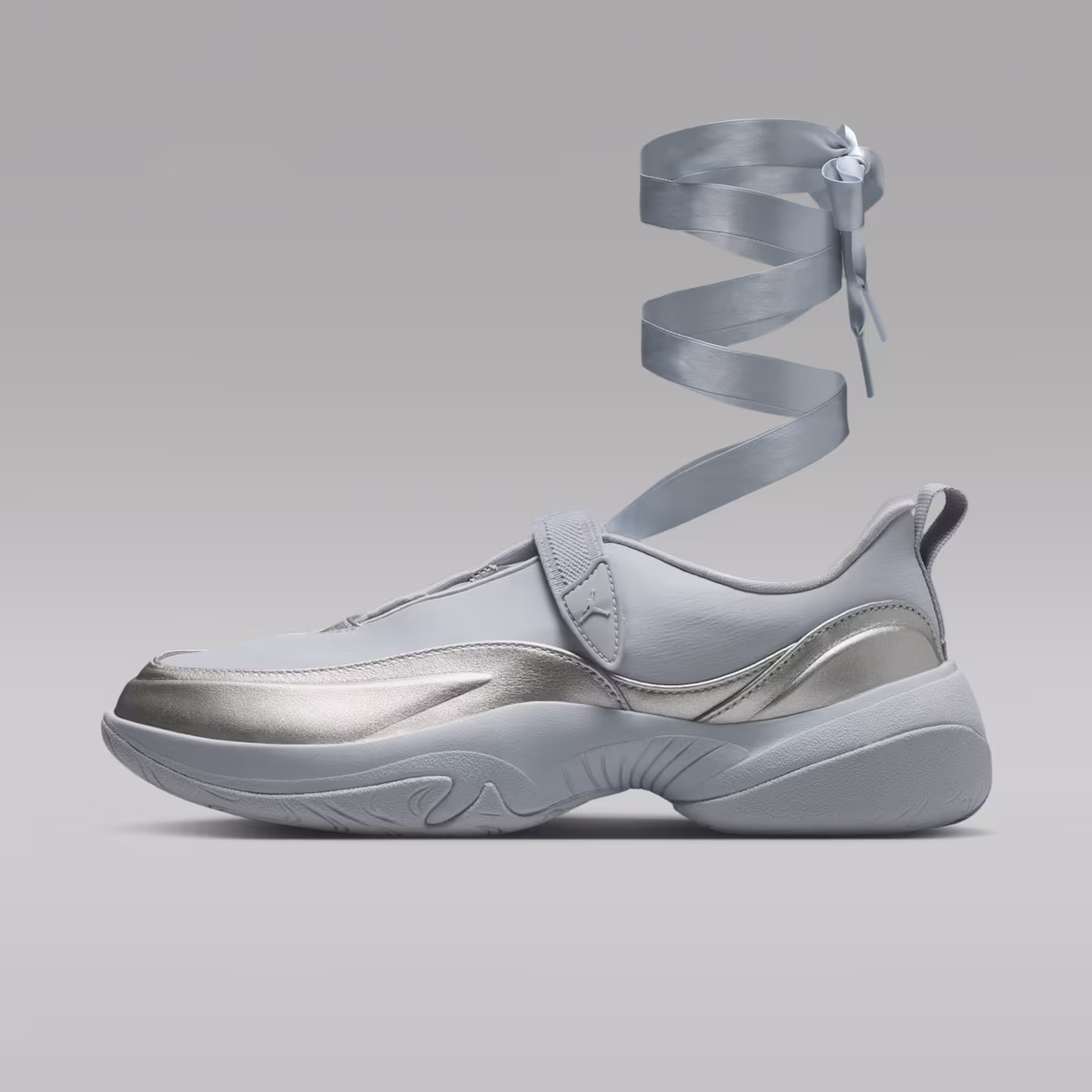 Light gray Jordan Pointe slip-on sneaker with metallic silver overlays, sculpted monochrome sole, adjustable midfoot strap with Jumpman logo, satin wraparound ribbon lace, and matching gray heel pull tab.