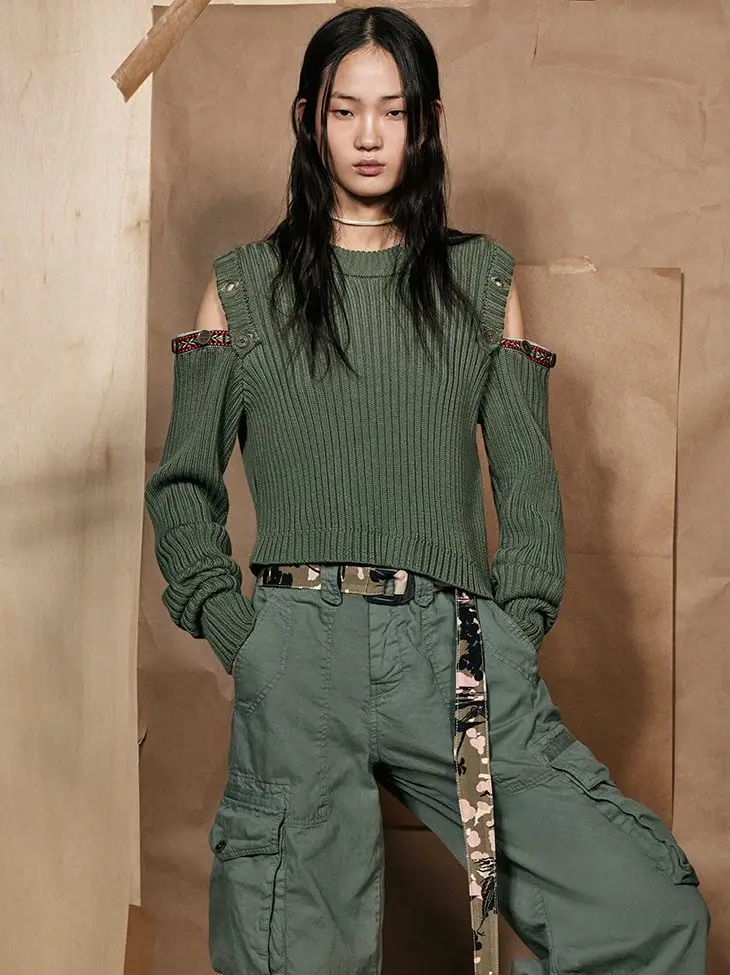 Model wearing an olive green ribbed cold-shoulder knit sweater with matching cargo trousers, a camouflage belt, and military-inspired details from the Zara SRPLS collection.