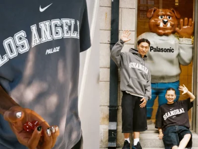 Lifestyle campaign image pairing a close-up of a Nike x Palace Los Angeles T-shirt with red dice in hand alongside two models wearing Shanghai hoodies and T-shirts posing in front of a storefront display with a large cartoon bulldog figure