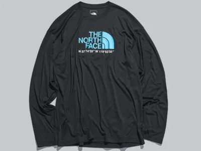 Black long-sleeve The North Face shirt with a blue chest logo and white geographic coordinates, displayed on a light gray background