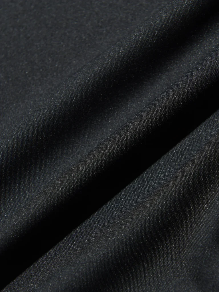 Macro view of the black technical fabric, highlighting its smooth weave and subtle sheen