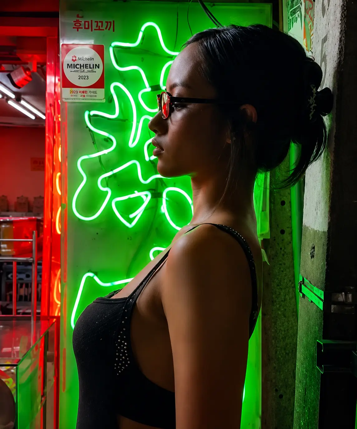 Cinematic portrait of a model wearing RSF Blades Series 2026 eyewear, standing beside vivid green neon signage with contrasting red ambient lighting, highlighting the collection's contemporary silhouette and glossy black frame.