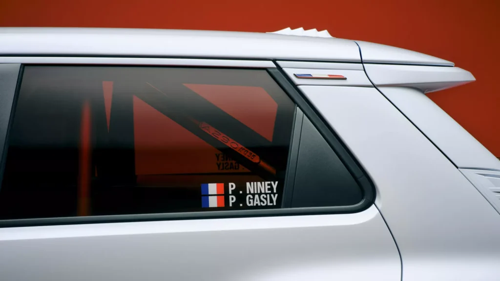 Close-up of the Alpine A290 Rallye rear side window showing Pierre Niney and Pierre Gasly name decals with French flags above the roll cage