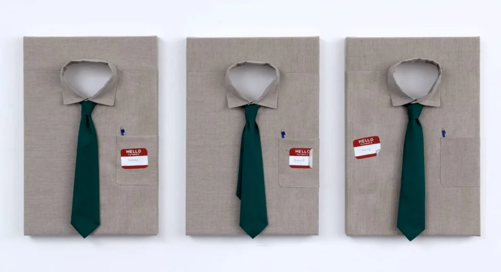 Three canvas artworks of beige dress shirts with green neckties, each displaying a different red-and-white "Hello My Name Is" badge placement and subtle office-themed details like a pen in the chest pocket