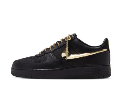 Lateral profile of the Nike Air Force 1 in black premium leather featuring a mirror-finish metallic gold Swoosh, gold chain laces, and black Air midsole
