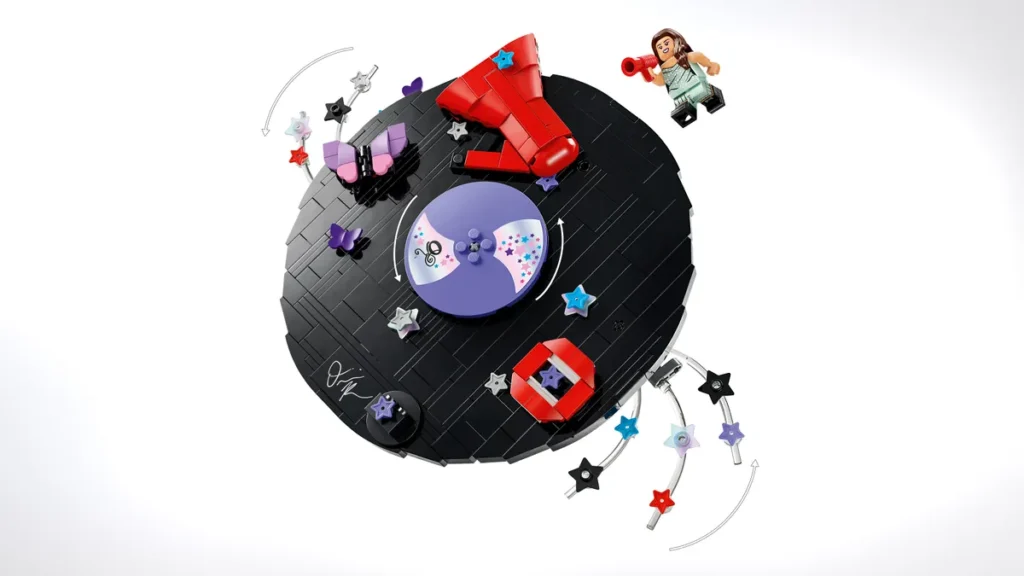 Top-down view of a circular black LEGO record player set with spinning purple disc, red elements, stars, butterflies, and an Olivia Rodrigo minifigure with megaphone float above