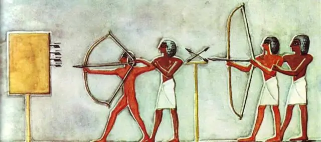 Ancient Egyptian wall painting depicting archers practicing with bows and arrows, showing four figures in white kilts aiming at a rectangular target against a pale painted background.