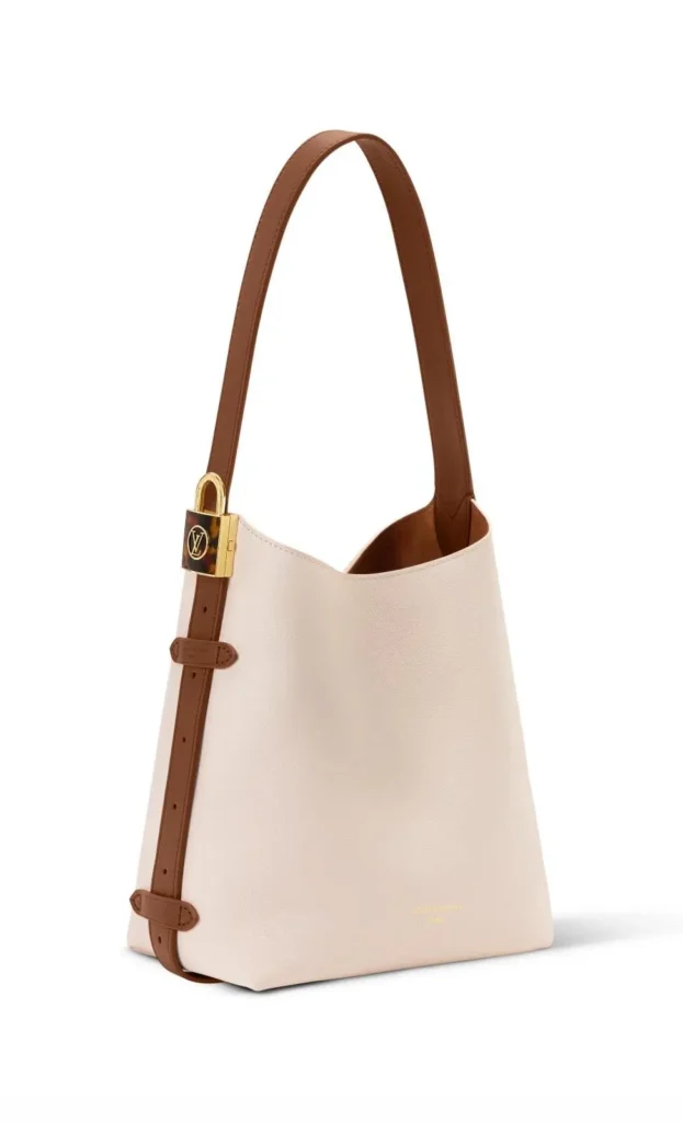 Cream and tan Louis Vuitton leather shoulder tote featuring a contrasting adjustable strap with gold buckle hardware and a min design