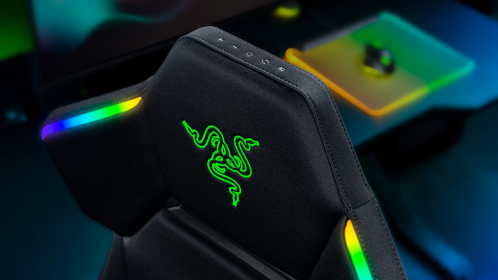 Angled rear close-up of the Razer gaming chair displaying the illuminated Razer logo, RGB Chroma shoulder lighting, and built-in headrest control