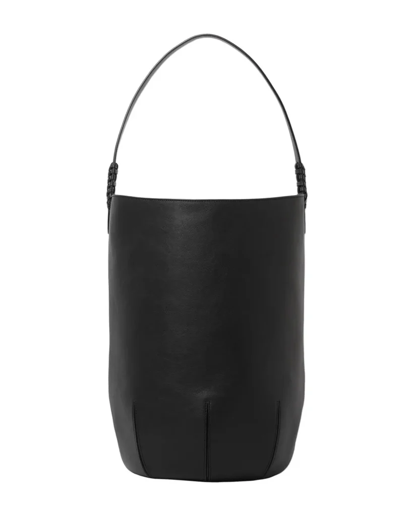 Black bucket-style leather shoulder bag with a clean cylindrical silhouette, slim shoulder strap, and minimalist detail
