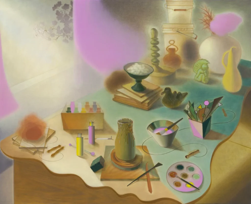 Surreal still life featuring books, ceramics, paintbrushes, artist tools, geometric objects, and pastel-colored vessels arranged across a softly illuminated tabletop with pink and mint tone