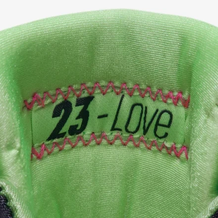Close-up of a green fabric tag inside the shoe reading '23-Love,' stitched with pink zigzag thread.
