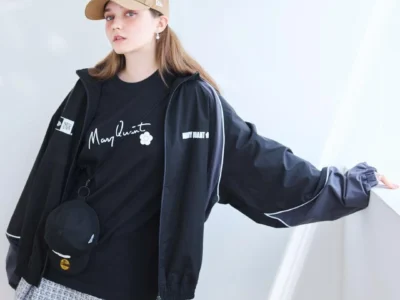 Model Wearing Mary Quant X New Era Cap, Black Shirt And Track Jacket In Studio
