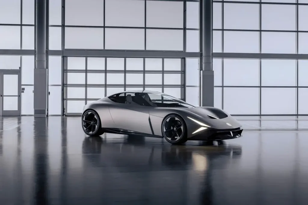 Acura NEXERA Vision concept car in matte silver display inside a bright industrial studio with expansive glass windows and a reflective floor