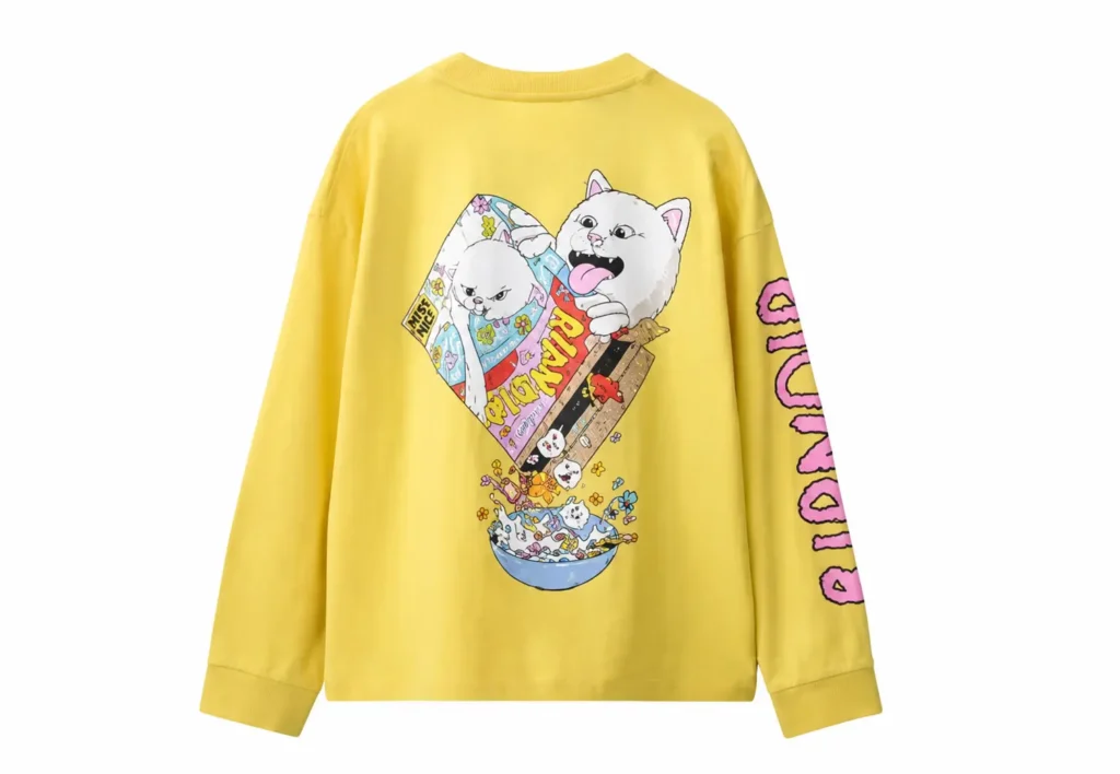 Yellow RIPNDIP long-sleeve shirt with a colorful cartoon cat cereal graphic and pink sleeve letter