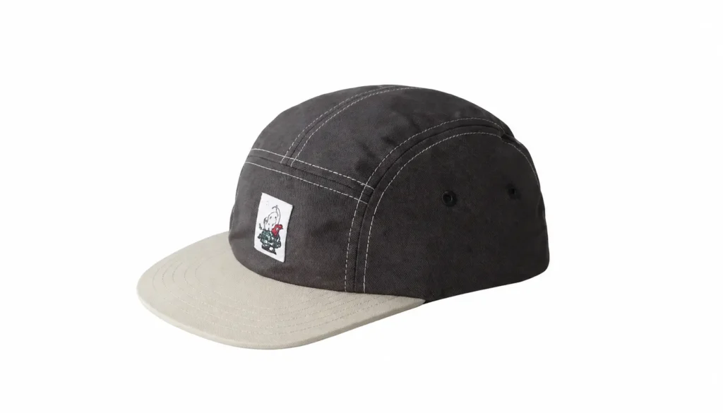 Black five-panel cap with contrast white stitch, cream brim, and small front graphic patch