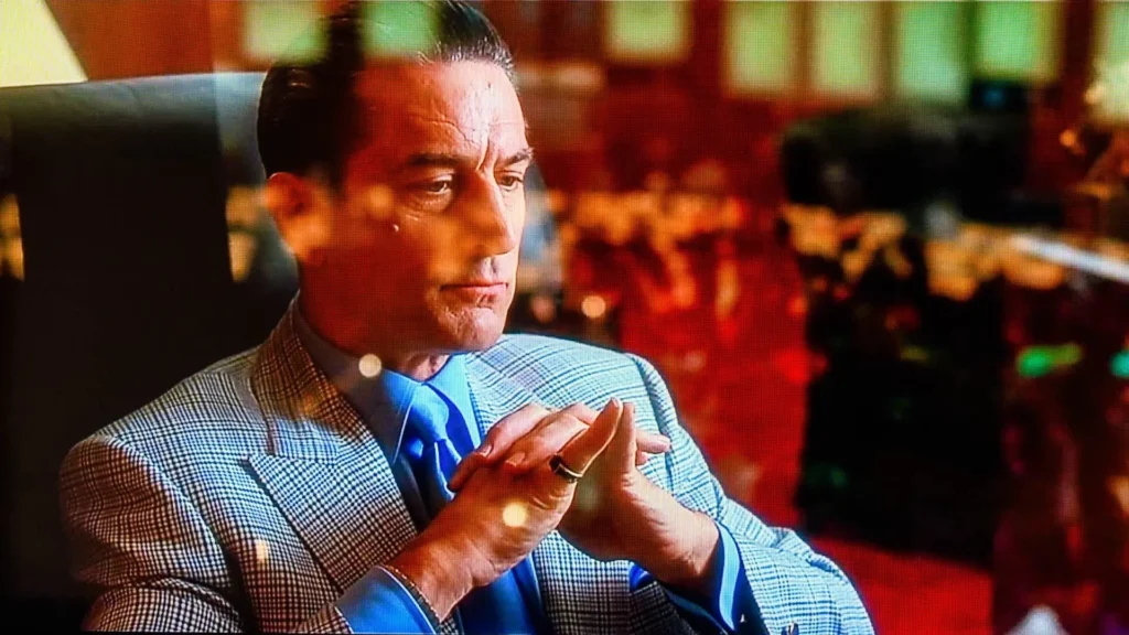 Robert De Niro sits with his hand clasp inside a casino in Casino