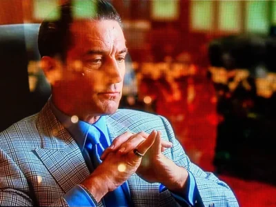 Robert De Niro sits with his hand clasp inside a casino in Casino
