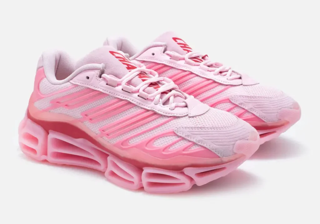 Angled view of the adidas x Willy Chavarria sneaker pair highlighting pale pink mesh uppers, suede mudguards, bold Three Stripes, oversized tubular sole units, and red Chavarria tongue brand