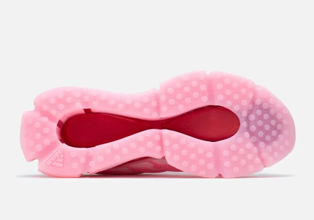 Bottom view of the adidas x Willy Chavarria shoe displaying the translucent pink rubber outsole, circular traction pattern, and constrast red midfoot insert