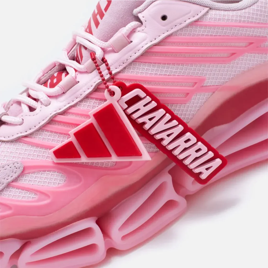Detailed close-up of the co-branded adidas and CHAVARRIA hangtag attached to the pink mesh upper with molded Three Stripes overlays and sculpted midsole