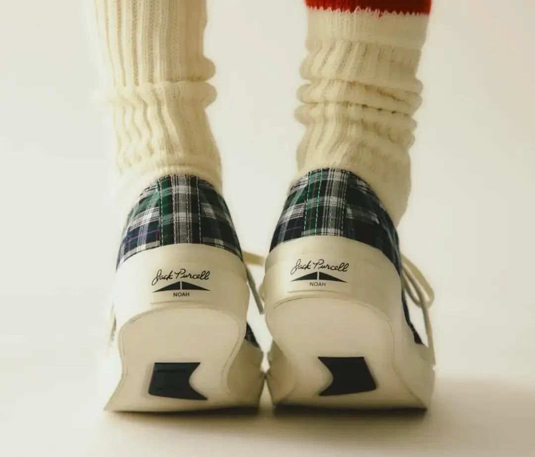 Rear View Of Noah X Jack Purcell Plaid Low-Top Shoes Worn With Cream Ribbed Socks, Showing Off-White Rubber Heels And Co-Branded Heel Labels.