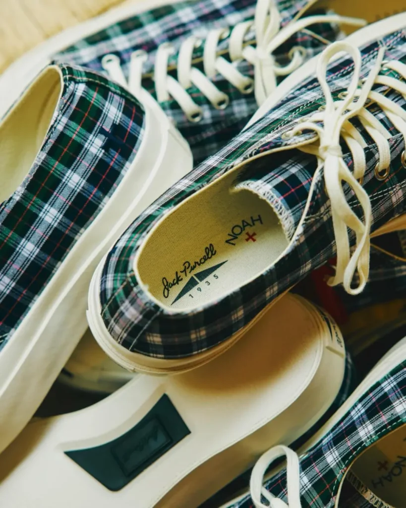 Close-up arrange of Noah x Jack Purcell plaid shoe highlight the dark green tartan uppers, white laces, off-white rubber construction, and co-brand insole
