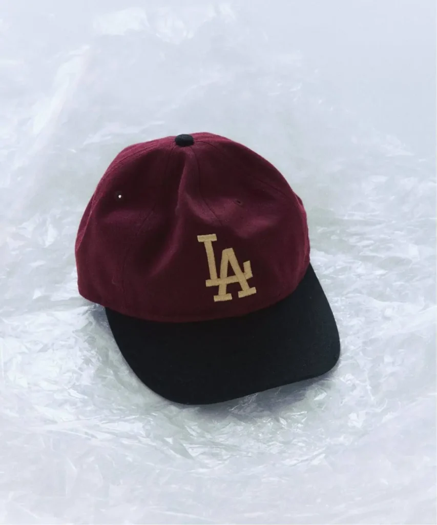 Burgundy and black baseball cap with a gold LA logo on a crinkled white surface