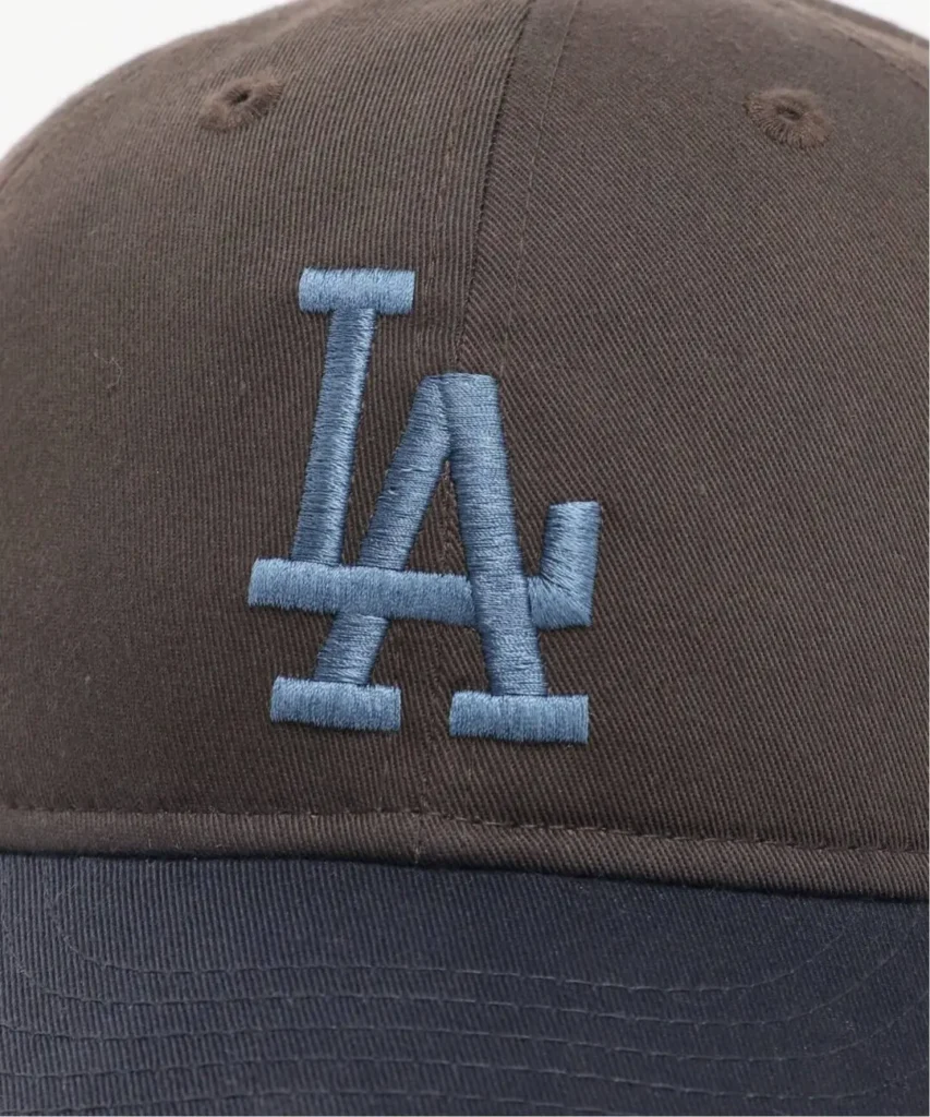 Close-up of a brown corduroy baseball cap with blue embroidered LA logo and ventilation eyelets