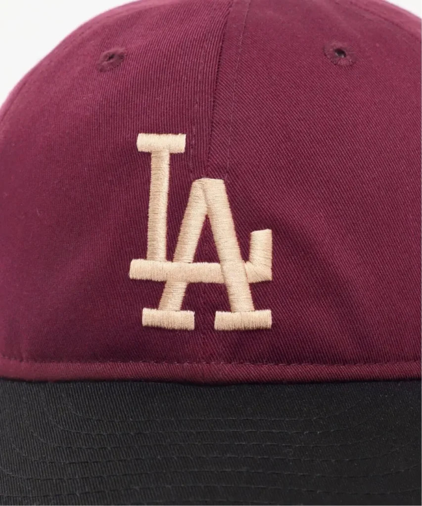 Close-up of a burgundy and black baseball cap with a cream embroidered interlocking LA logo
