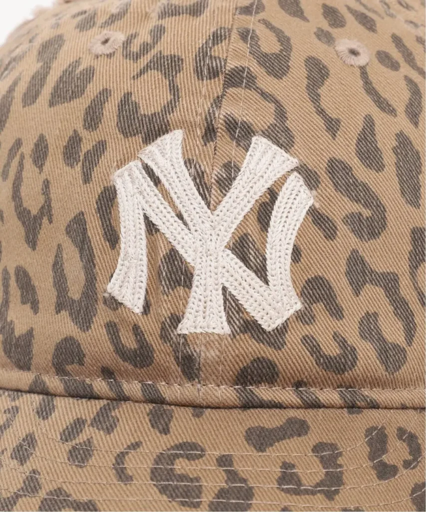 Close-up of a tan leopard-print cap with a raised white embroidered letter M on the crown