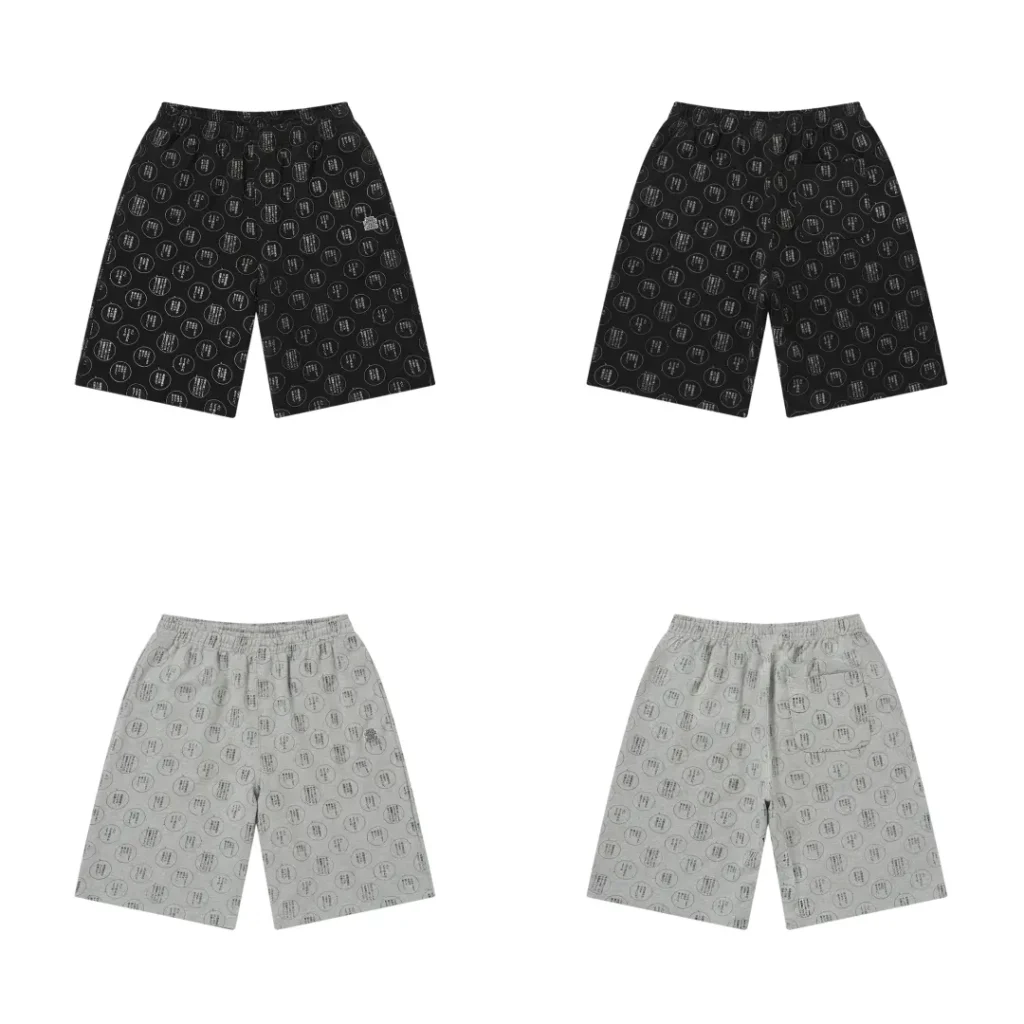 Four pairs of allover-print shorts in black and sage grey, front and back, covered in a repeating pattern of Japanese-text speech bubble