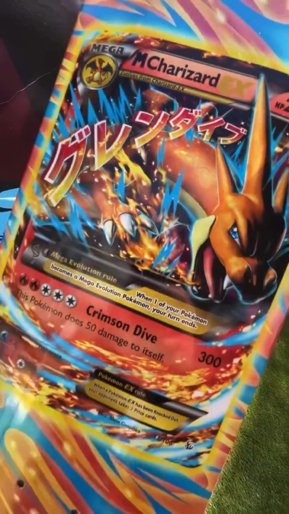 Close-up of a Pokémon Mega Charizard trading card with Japanese text and colorful blue, orange, and red artwork