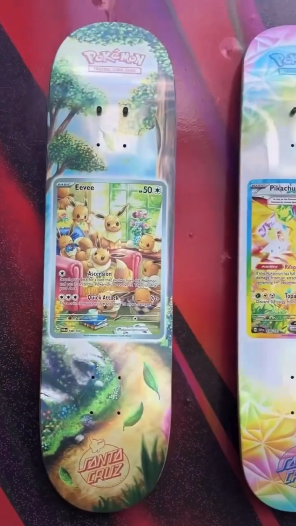 Pokémon-themed Santa Cruz skateboard deck featuring an Eevee trading card and forest artwork beside a Pikachu deck