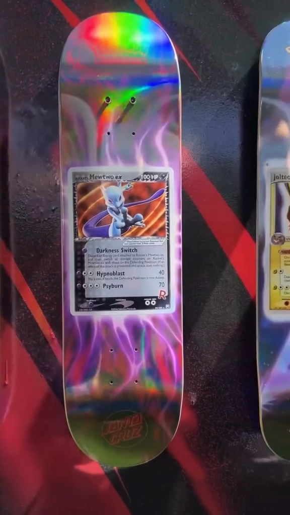 Colorful Pokémon skateboard deck featuring a Mewtwo trading card mounted at the center