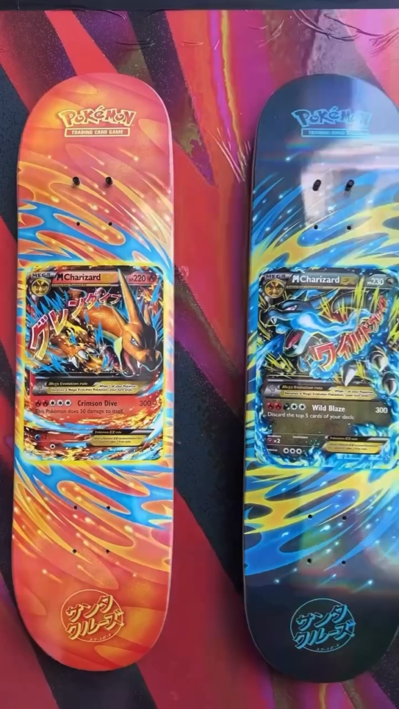 Two Pokémon Charizard trading card-themed skateboards, one red-orange and one blue, leaning against a colorful backdrop