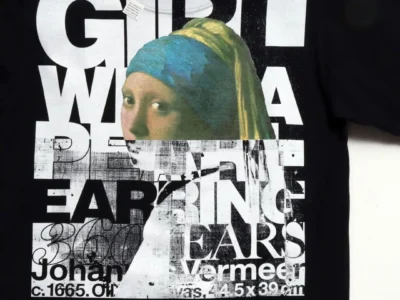 Black graphic Tee feature Johannes Vermeer's Girl with a Pearl Earring layered over oversized distressed typography in a collage-style print with museum-inspired brand