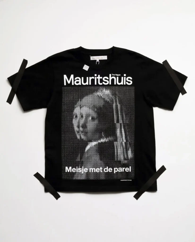 Black Tee with a monochrome pixel-grid version of Girl with a Pearl Earring and bold Mauritshuis brand across the chest