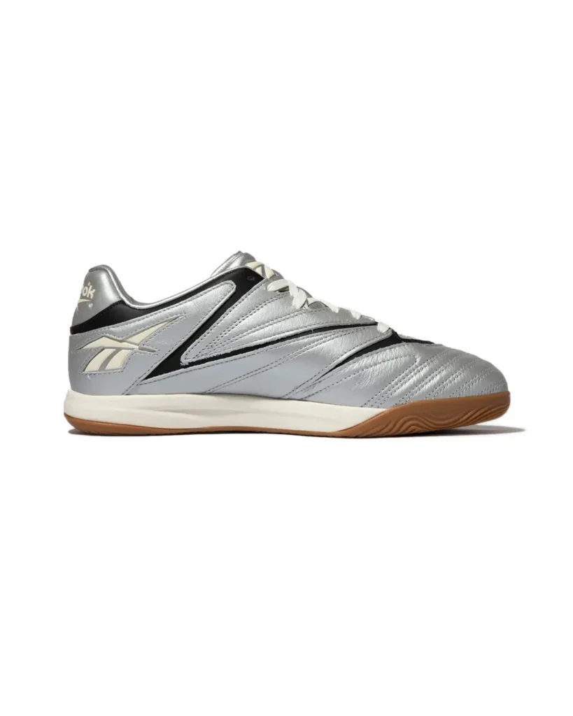 Side profile of the Reebok Sidewinder 96 ID in metallic silver with black overlay, cream midsole and gum outsole against a white background