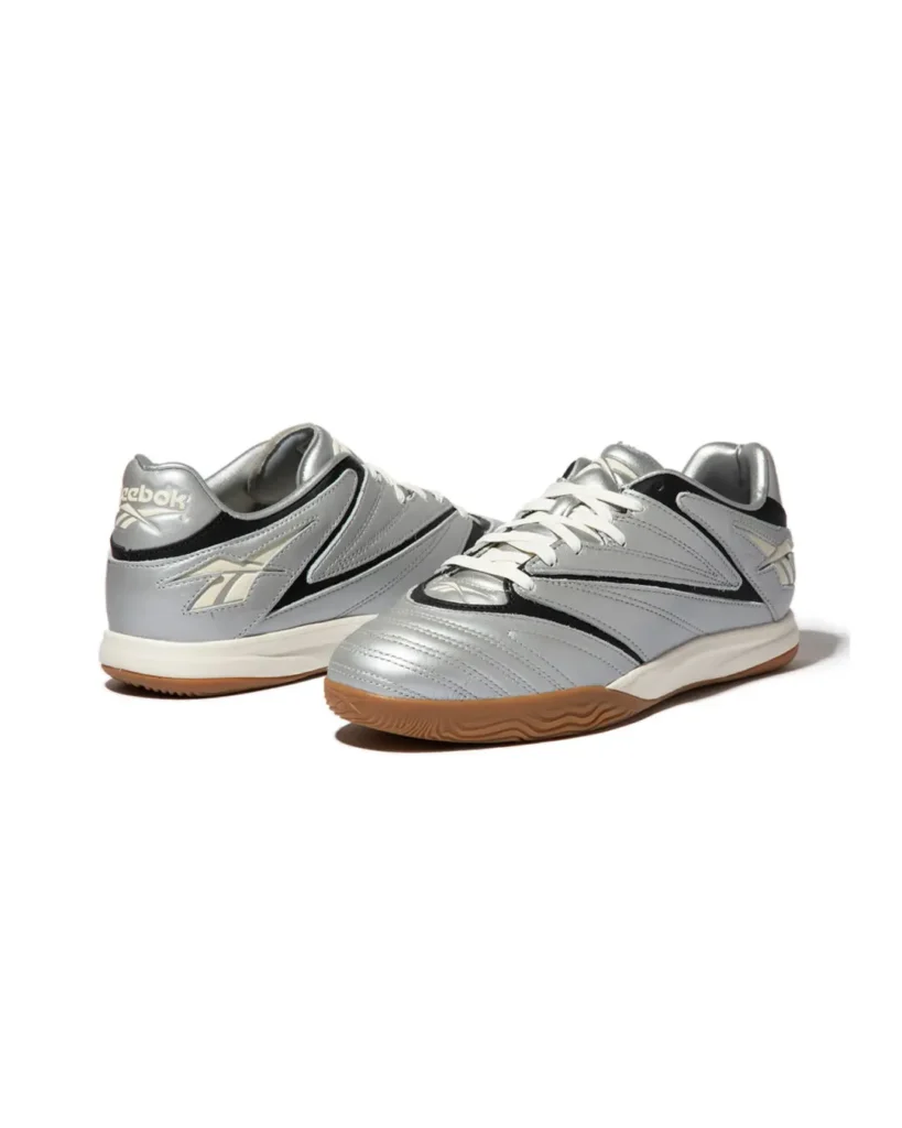 Pair of Reebok Sidewinder 96 ID shoe in metallic silver and black with cream midsoles and gum outsole, photograph against a white background